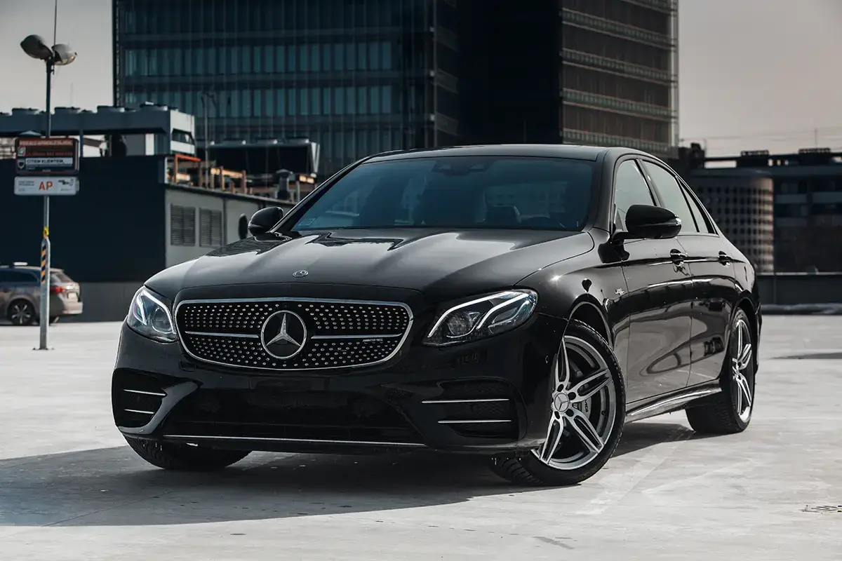 Berline Mercedes-Benz Classe E noire stationnée sur un toit-terrasse urbain, vue avant-gauche.